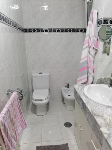 a white bathroom with a toilet and a sink at Piso en pleno centro de Miño derecha in Miño