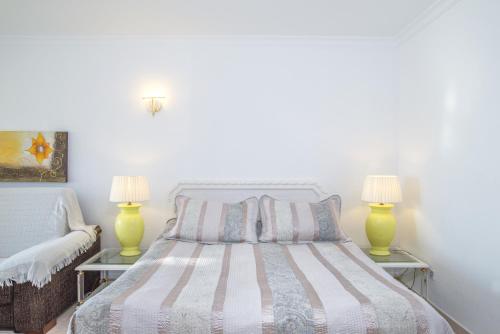 a white bedroom with a bed with two lamps at Penthouse studio with sea views in La Cala de Mijas
