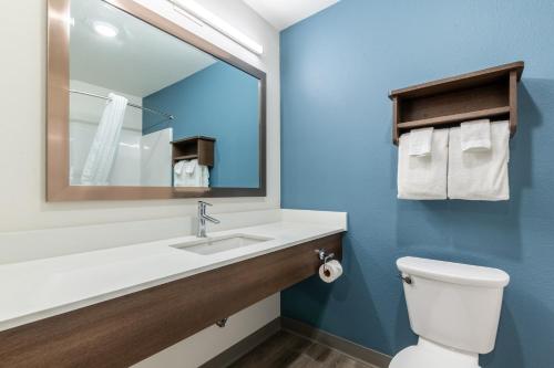 a bathroom with a sink and a mirror and a toilet at WoodSpring Suites Gurnee - Chicago in Gurnee