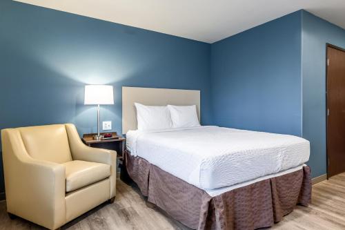 a bed and a chair in a room with blue walls at WoodSpring Suites Gurnee - Chicago in Gurnee