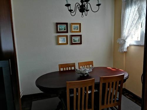 a dining room table with four chairs and a chandelier at PISO EN PLENO CENTRO DE MIÑO in Miño
