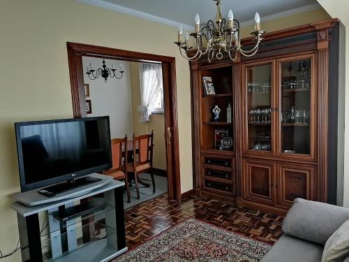 a living room with a television and a chandelier at PISO EN PLENO CENTRO DE MIÑO in Miño