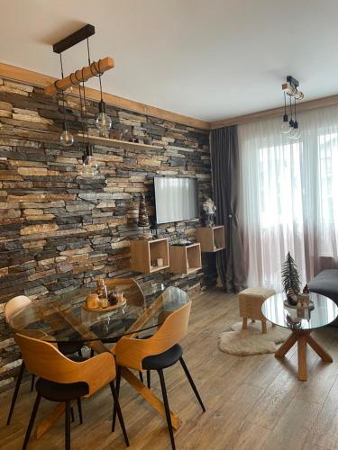 科帕奥尼克Silver Kop apartmani的客厅设有石墙和桌椅