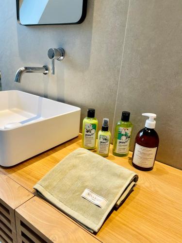 a bathroom counter with two bottles of soap and a sink at La Maison Rouge in Steenwerck