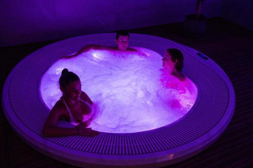 a man and two women sitting in a hot tub at Hôtel Spa Marotte in Amiens