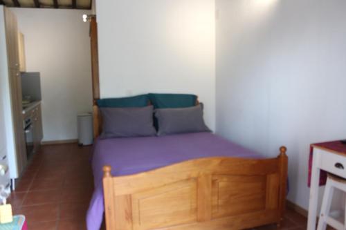 um quarto com uma cama de madeira com lençóis roxos e almofadas azuis em Mas de l'Olivier em Saint-Estève