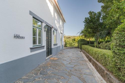 a walkway outside of a white house with a window at Casa Fundeira - Quinta dos Esconhais in Castanheira de Pêra