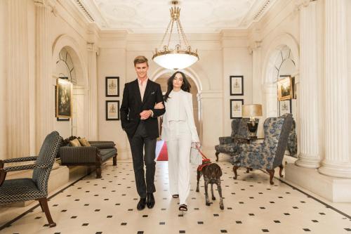 a man and a woman walking a dog in a hallway at The Lanesborough, Oetker Hotels in London