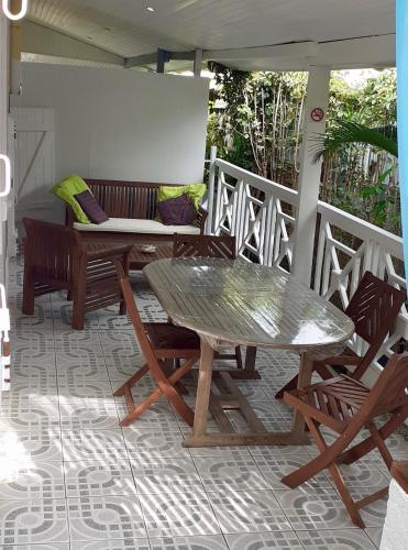 a patio with a table and chairs on a porch at La plage de Petit-Havre in Le Gosier