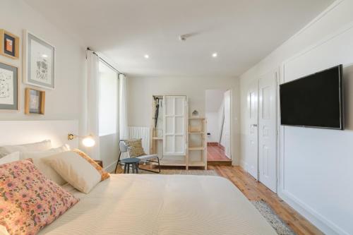 a bedroom with a bed and a flat screen tv at Casa Fundeira - Quinta dos Esconhais in Castanheira de Pêra