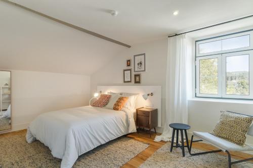 a white bedroom with a bed and a window at Casa Fundeira - Quinta dos Esconhais in Castanheira de Pêra