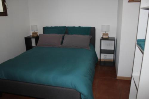 łóżko z zieloną pościelą i poduszkami w pokoju w obiekcie Mas Fany et Olivier w mieście Saint-Estève