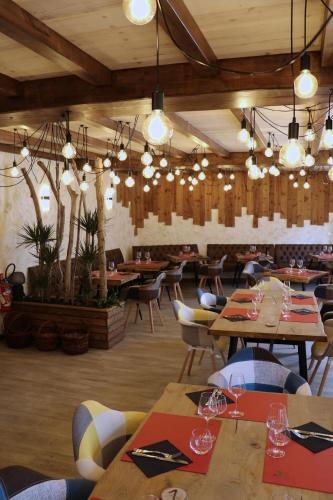 une salle à manger avec tables, chaises et lustres dans l'établissement Auberge du Grand Champ, à Lalley
