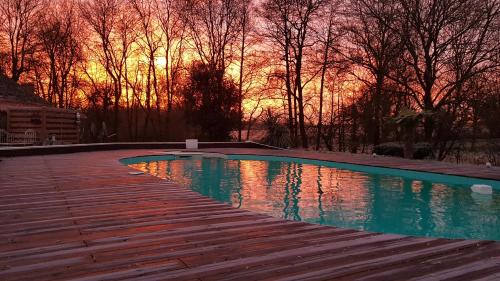- une piscine sur une terrasse en bois avec un coucher de soleil en arrière-plan dans l'établissement Le Nichoir, à Les Essarts