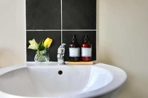 a white sink with two bottles and a vase of flowers at Lovely Twin Bed Studio Near Coventry Shopping Centre in Coventry