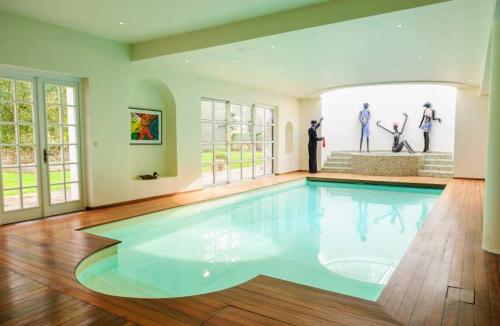 a large swimming pool in a large room with windows at La chambre des vignerons in Montreuil-aux-Lions