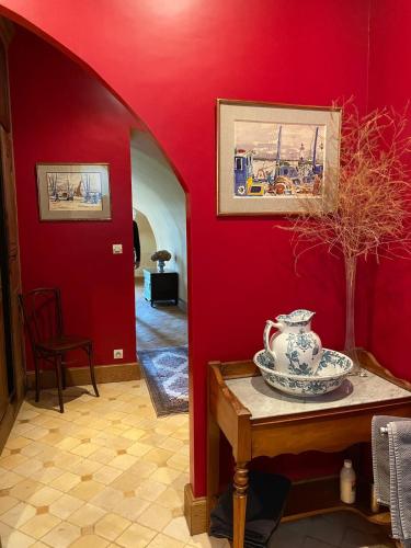 a red room with a table with a vase on it at La chambre des vignerons in Montreuil-aux-Lions