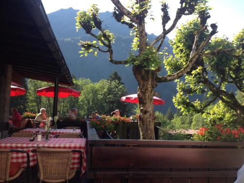 a table with red umbrellas in a restaurant with a tree at Alpengasthof Hotel Schwand in Oberstdorf
