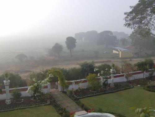 a house with a garden and a foggy field at Jheelam Homestay in Bhopal