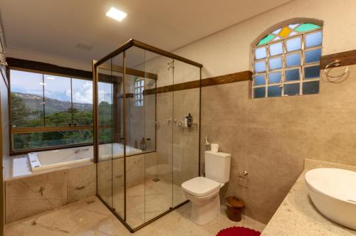 a bathroom with a shower and a toilet and a sink at Sitio Jatoba/Lapinha da Serra in Santana do Riacho
