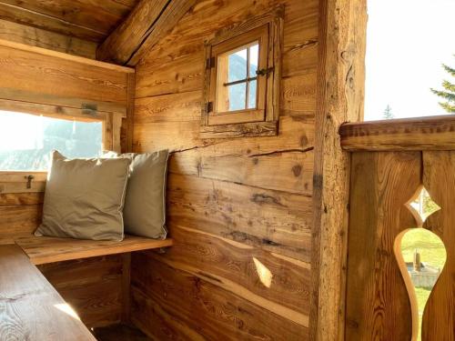 un banco en una cabaña de madera con ventana en LA PLACETTE - Albergo diffuso e trattoria, en Usseaux