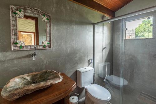 a bathroom with a toilet and a sink and a mirror at Sitio Jatoba/Lapinha da Serra in Santana do Riacho