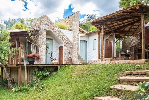 a stone house with a garden and a patio at Sitio Jatoba/Lapinha da Serra in Santana do Riacho