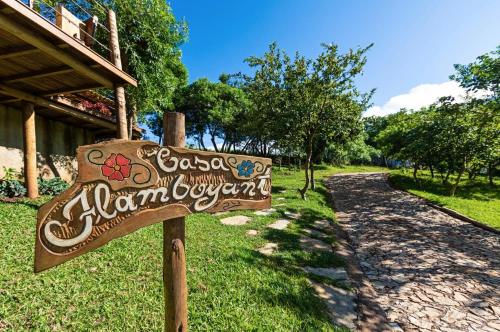 a wooden sign in the grass next to a path at Sitio Jatoba/Lapinha da Serra in Santana do Riacho