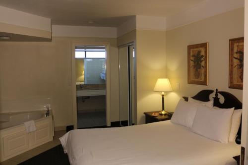 a hotel room with a bed and a bathroom at Imperial Swan Hotel and Suites Lakeland in Lakeland