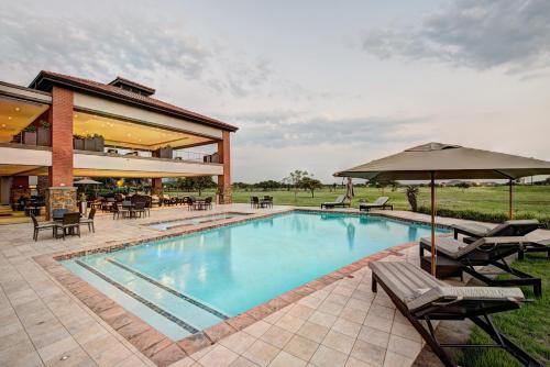 a large swimming pool with chairs and an umbrella at Royal Marang Hotel in Phokeng