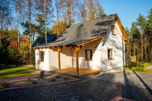 a small white house with a black roof at Domek Julia z banią ruską i sauną in Sulęczyno