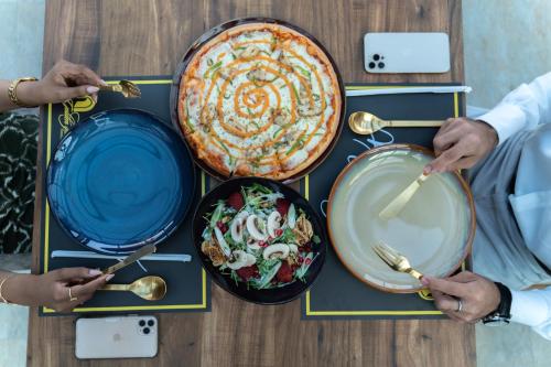 a group of people sitting at a table with plates of food at Golden Tower Hotel Al Khobar Corniche in Al Khobar