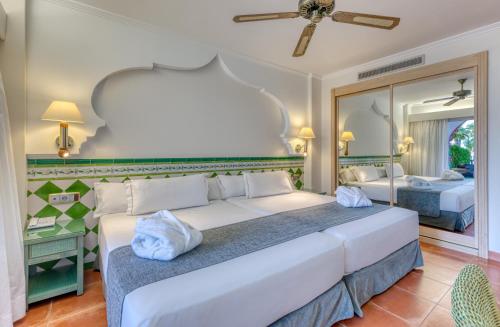 a bedroom with a large white bed and a mirror at Playacálida in Almuñécar