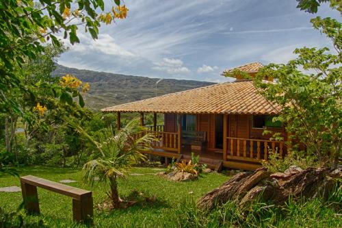 a wooden house with a bench in front of it at Sitio Jatoba/Lapinha da Serra in Santana do Riacho
