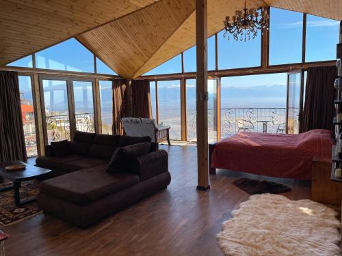 a living room with a couch and a bed and glass windows at Guest House Kusika in Sighnaghi