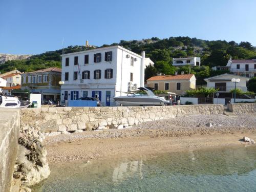 a beach with a building and a boat in the water at Apartment & studio Elizabet in Baška