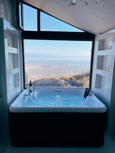 a bath tub in a room with a large window at Guest House Kusika in Sighnaghi