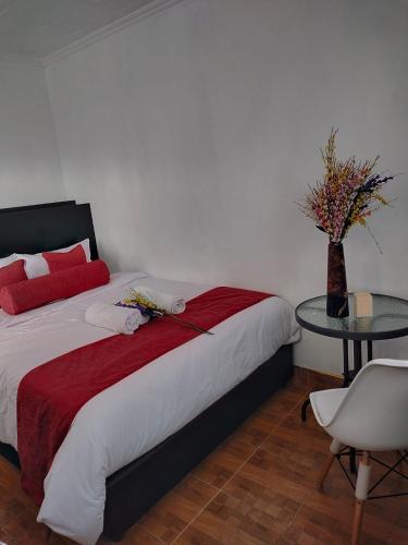 a bedroom with a bed with a table and a vase with flowers at Bloom 2 private home in Thika