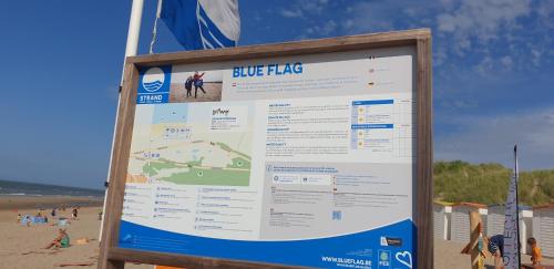 a sign at the beach with a blue flag at Tedy style in De Haan