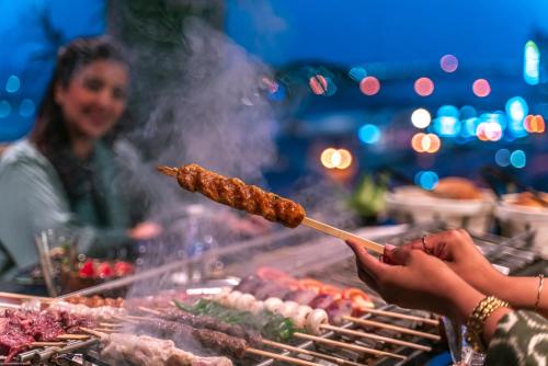 a person is cooking food on a grill at Golden Tower Hotel Al Khobar Corniche in Al Khobar