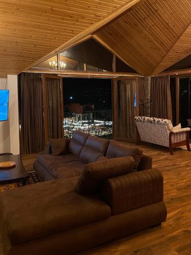 a living room with a brown couch and a television at Guest House Kusika in Sighnaghi