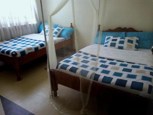 2 Betten in einem blau-weißen Zimmer in der Unterkunft Baraka Home in Nairobi