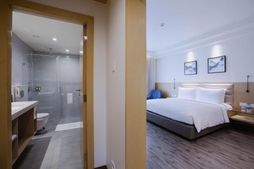 a bedroom with a bed and a bathroom with a shower at IKON By Annapoorna in Coimbatore