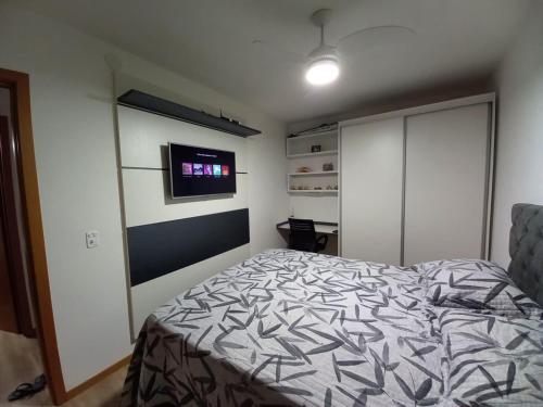 een slaapkamer met een bed en een flatscreen-tv bij Apartamento aconchegante à 200m Praia de Piçarras in Piçarras