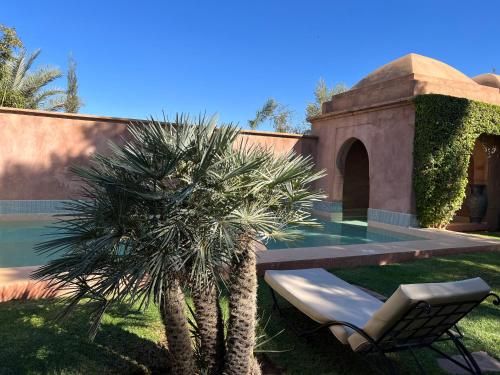 a chair and a palm tree in front of a house at Villa #1 ‘Rosalie’ in Marrakech