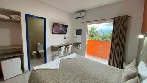 a bedroom with a bed and a bathroom with a window at Kaliman Pousada in Ubatuba