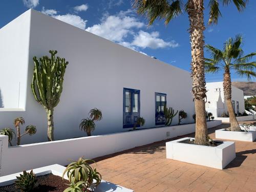 a white building with palm trees in a courtyard at Casa Sol Azul in Puerto Calero