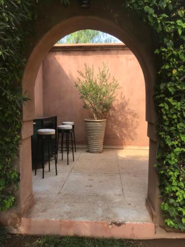 an archway with chairs and a potted plant on a patio at Villa #1 ‘Rosalie’ in Marrakech