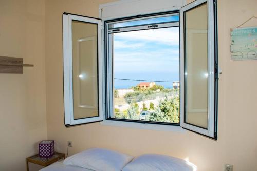 a bedroom with a window with a view of the ocean at Nina Villa Cretevasion in Anópolis
