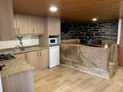 una cocina con armarios de madera y una pared de piedra. en "Casa do Avô Armindo" Mountain Experience en Vila Real